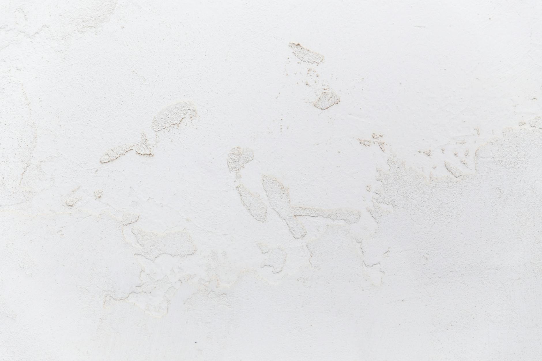 white shabby concrete wall with cracked stucco